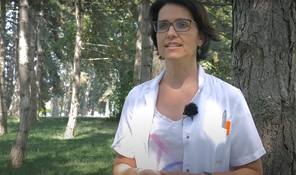 Ärztin steht in einem Park vor Bäumen und erklärt COPD